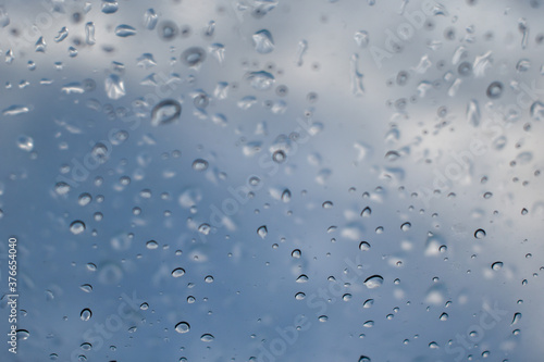 Raindrops on the window pane. Dew or condensation texture on a window against a blue sky. Selective focus on raindrops.