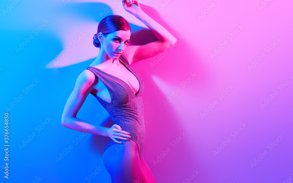 High Fashion. Woman in colorful neon light, make-up. Sexy girl, stylish hair, trendy bodysuit, makeup. Party disco neon style. Creative art beauty concept, fashionable fitness model, bright color