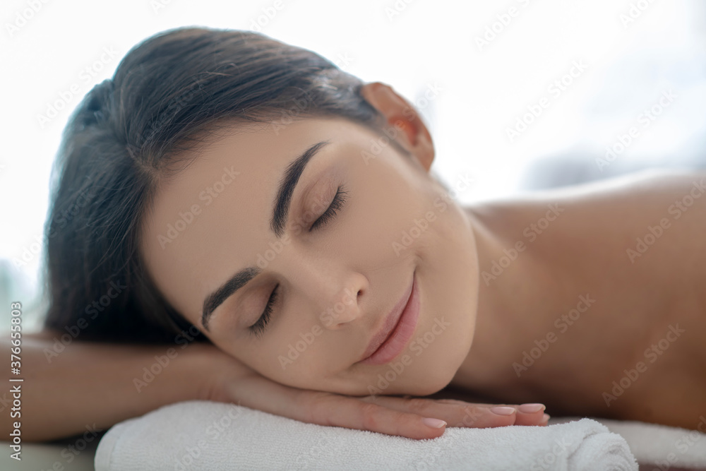 Dark-haired woman lying down after beauty procedures Dark-haired woman lying down after beauty procedures