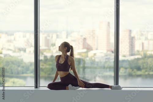 Young beautiful woman training with a view of the city in the background. The concept of health and motivation, stretching and training in the gym.