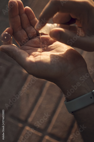 Vertical shot of a man's hand putting hand sanitizer on a blurred background - pandemic COVID-19