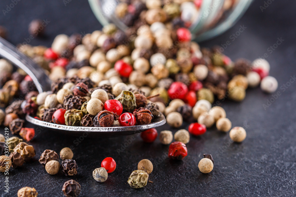 mix of peppercorns on a dark stone background mix of peppercorns on a dark stone background