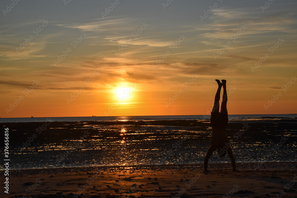silhouette of a man doing workout on a beach and a sunset in the background