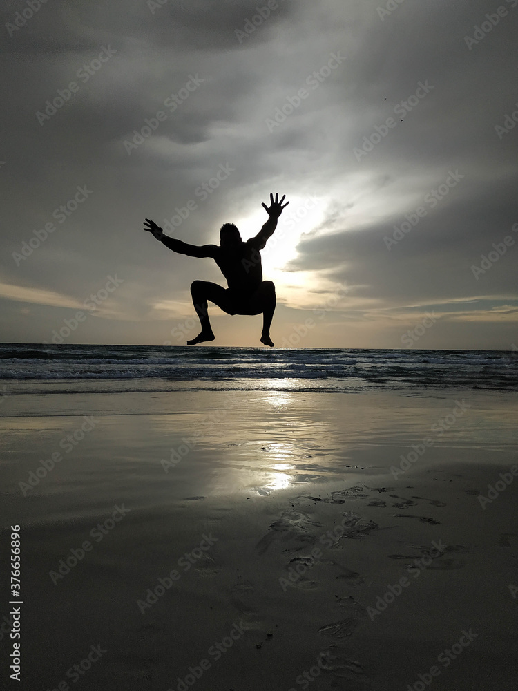 Sunset in the beach with a men silhouette jumping with the arms open