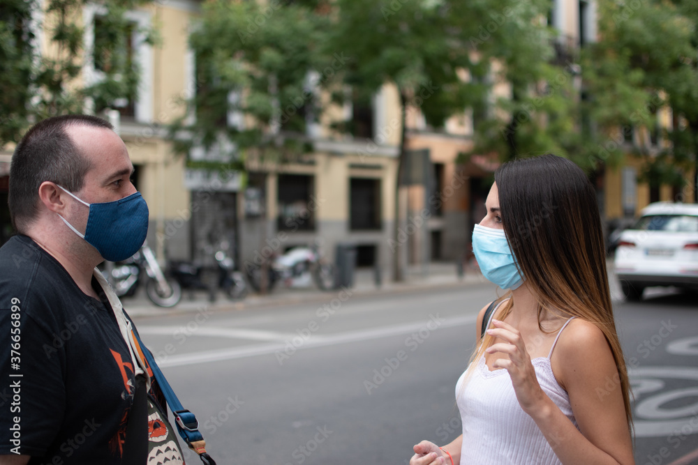 Young girl wearing a medical mask talking to a man with a mask - new normal