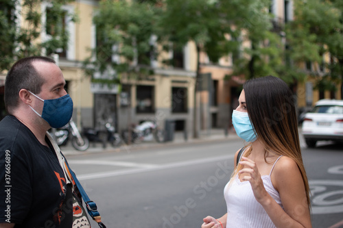 Young girl wearing a medical mask talking to a man with a mask - new normal