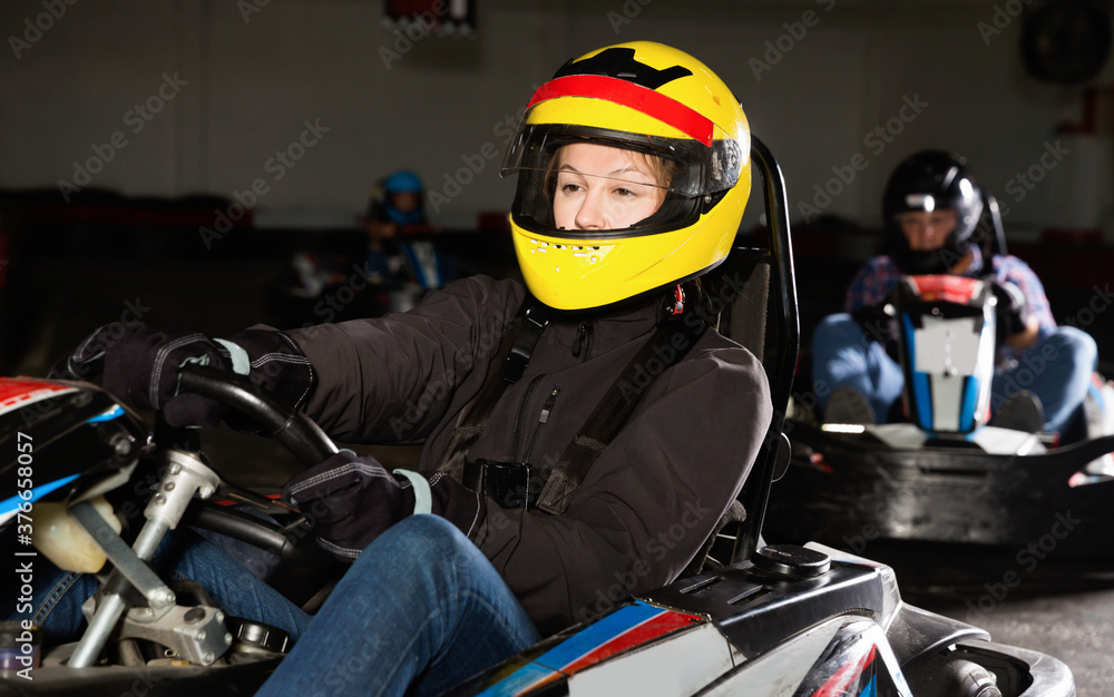 Glad positive smiling woman driving sport car for karting in a circuit lap in sport club