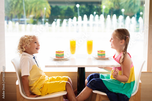 Photography Kids eat cake at restaurant. Boy and girl in cafe.