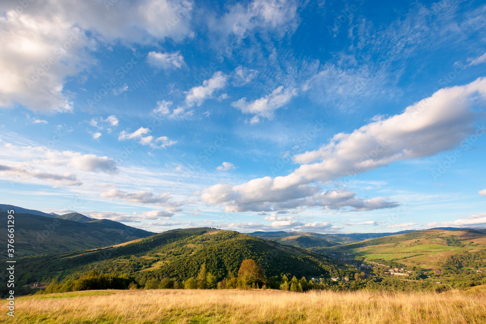 Fototapeta premium beautiful carpathian countryside. sunny afternoon. wonderful autumn landscape in mountains. rural scenery with agricultural fields on rolling hills. watershed ridge in the distance