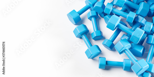 Heap of realictis blue dumbbells on the white table. Top view with copy space.