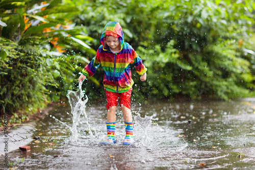 Kids in puddle in autumn rain. Waterproof wear