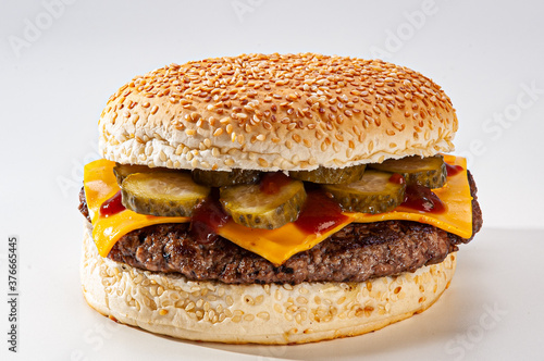 .Hamburger with sesame bread, melted cheddar cheese, pickles, and mayonnaise on white background. photo