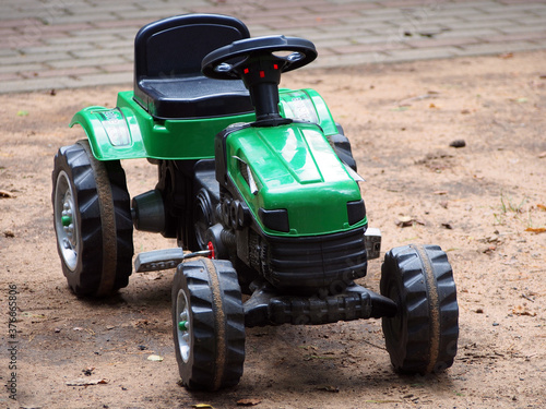 Obraz na płótnie A children's toy tractor with a pedal drive stands on the Playground. Educational toys for children, outdoor activities. w salonie