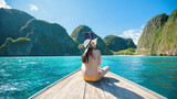 View of woman in swimsuit enjoying on thai traditional longtail Boat over beautiful mountain and ocean, Phi phi Islands, Thailand