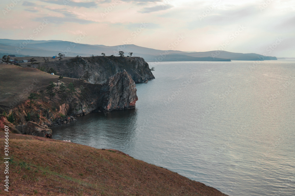 rocks cliffs stand on the shore of lake baikal, sunset, overcast