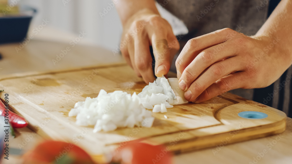 Close Up Shot of a Man Chopping an Onion with a Sharp Kitchen Knife. Preparing a Healthy Organic Meal in a Modern Kitchen. Natural Clean Diet and Healthy Way of Life Concept.