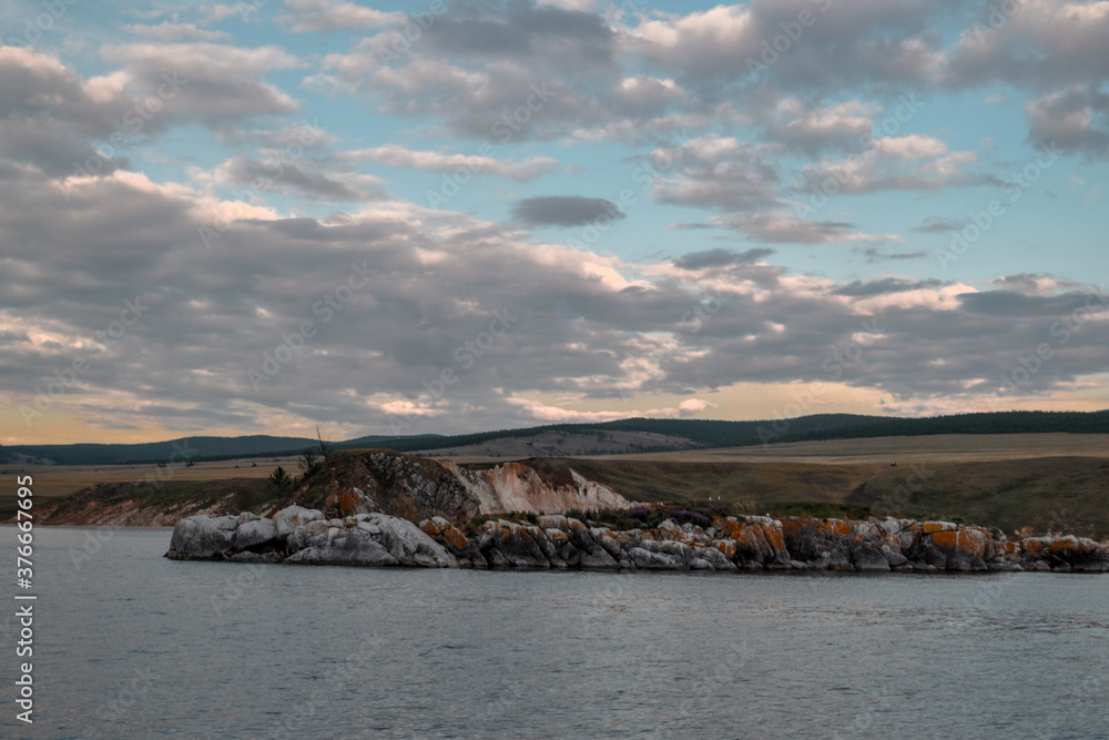 warm evening with large clouds on Lake Baikal, Rocky rocky shore with cliffs.
