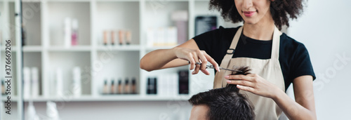 Close up of hairdresser cutting hair of man in beauty salon interior, panorama, free space