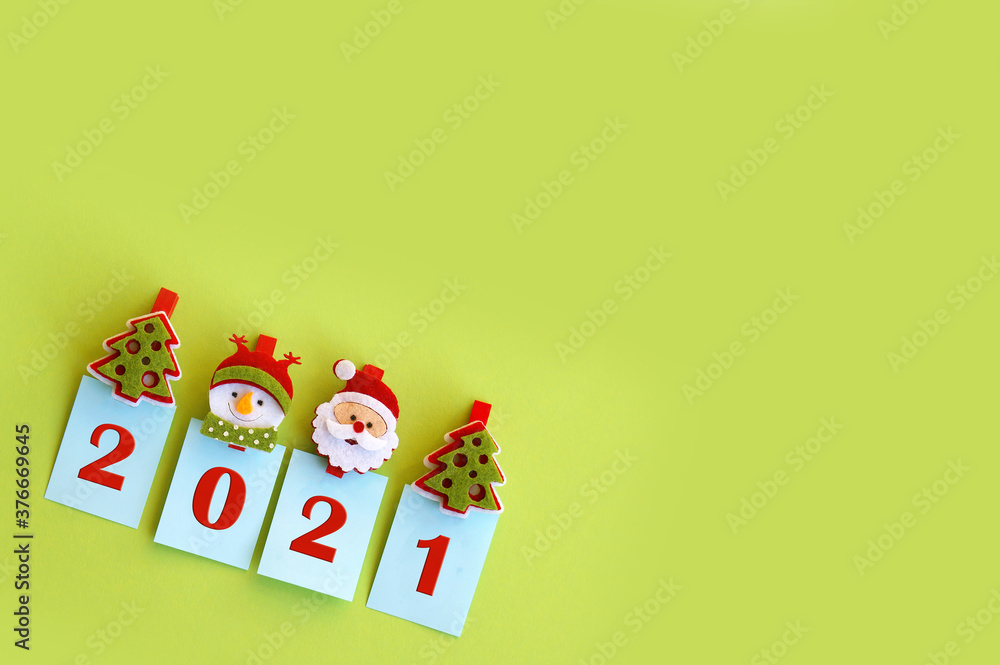 Fototapeta premium Year 2021 on a green background and symbols of the winter holiday.