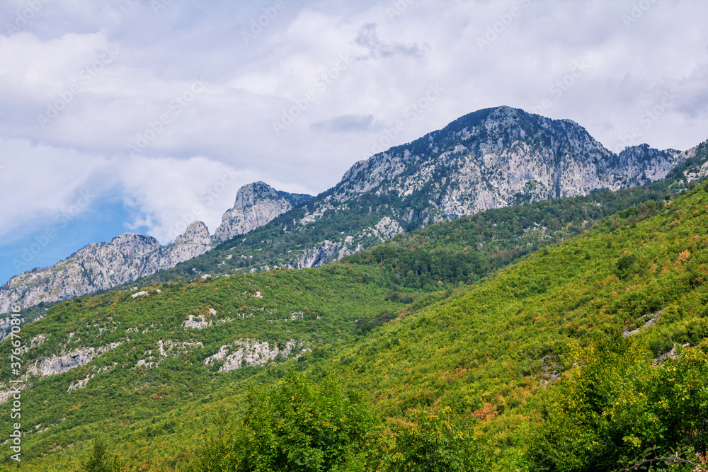 Summer landscape – Albanian mountains, covered with green trees, clouds on blue sky