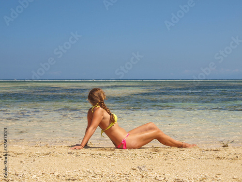 Paradise beach in shades of blue with turquoise water, mountains in the background and a woman lying on the shore