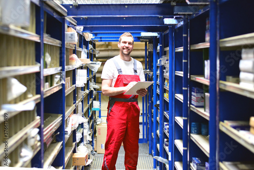 car repair shop employees in the warehouse for spare parts for repairing cars in a garage