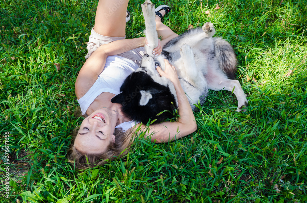young beautiful girl lying on the grass playing with her dog young beautiful girl lying on the grass playing with her dog