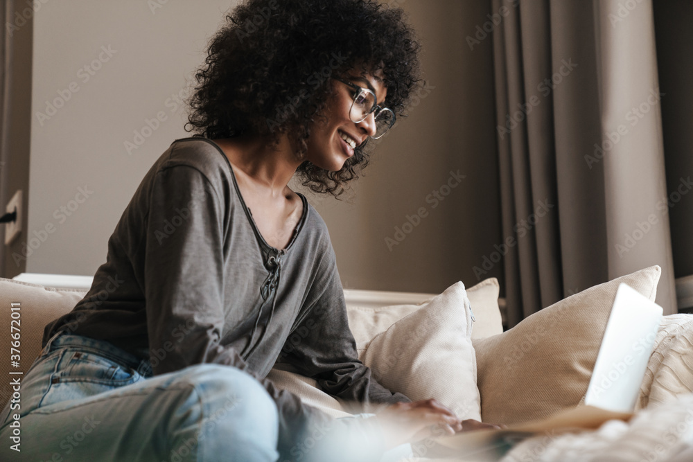 Image of woman working with laptop while sitting on sofa Image of woman working with laptop while sitting on sofa