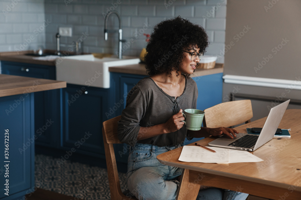 Image of woman drinking coffee while working with laptop Image of woman drinking coffee while working with laptop