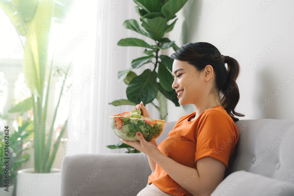Close up portrait of young woman with long hair sitting on sofa at home and eating healthy food. Close up portrait of young woman with long hair sitting on sofa at home and eating healthy food.