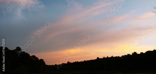 Fototapeta Naklejka Na Ścianę i Meble -  AMAZING VIEW OF SUNSET OVER THE MOUNTAINS.MESMERIZING COLORS OF SKY  ON A SPRING DAY IN KERALA