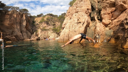young man jumping in to the sea from a cliff in costa brava