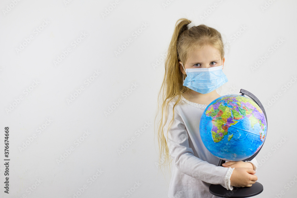 A sad child looks at the camera in a protective mask and holds a globe. The concept of isolating the world from a new generation virus A sad child looks at the camera in a protective mask and holds a globe. The concept of isolating the world from a new generation virus