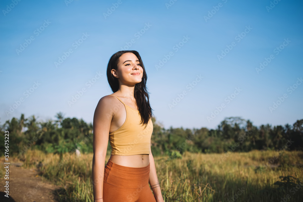 Positive slim beautiful woman enjoying training on nature field on sunny day enjoying relaxation, smiling caucasian girl inspiring with meadow resting and feeling body vitality for healthy body Positive slim beautiful woman enjoying training on nature field on sunny day enjoying relaxation, smiling caucasian girl inspiring with meadow resting and feeling body vitality for healthy body