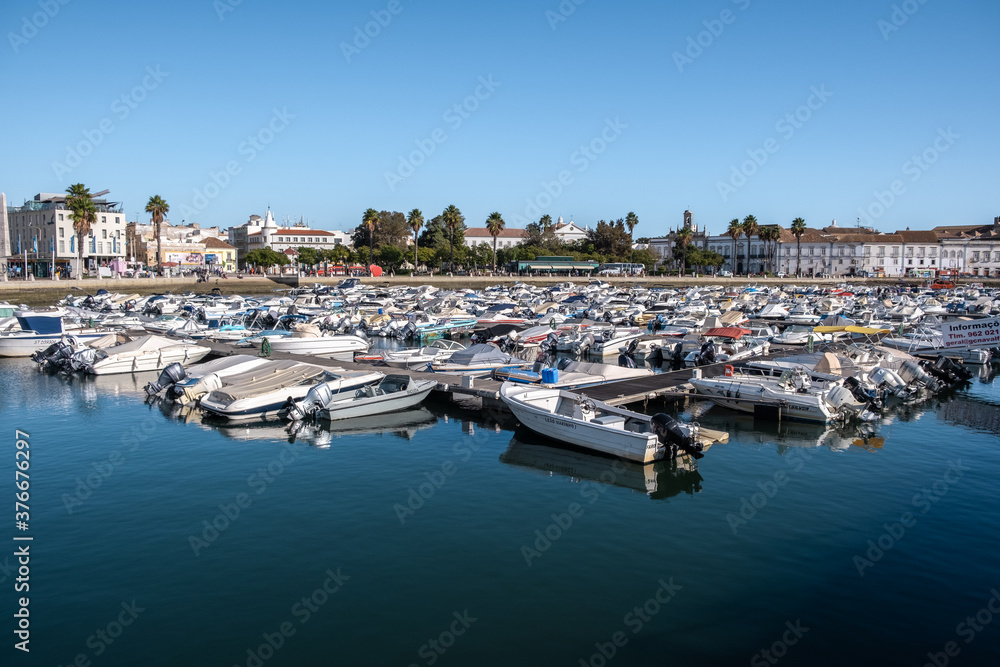 Boats At The Marina Of Faro With Water Reflection And Clear Blue Sky In Algarve, Portugal.