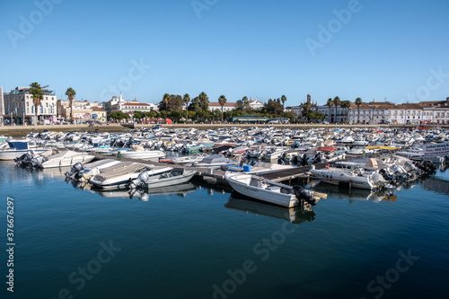 Boats At The Marina Of Faro With Water Reflection And Clear Blue Sky In Algarve, Portugal.