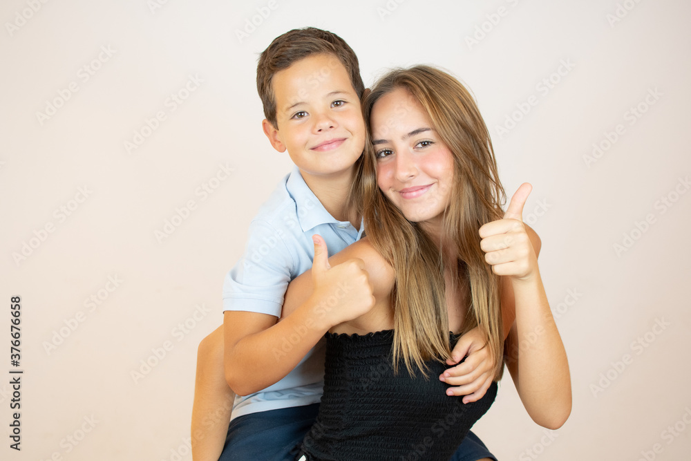 Two smiling brothers with thumbs up on white background Two smiling brothers with thumbs up on white background