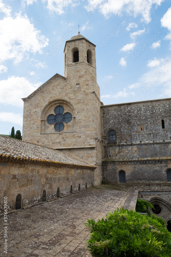 The beautiful backyard with ancient stone architecture and the blossoming garden of the medieval christian abbey in the mountain valley of Pyrenees in France The beautiful backyard with ancient stone architecture and the blossoming garden of the medieval christian abbey in the mountain valley of Pyrenees in France