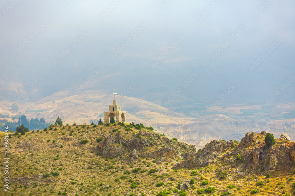 Chapel and cross in the mountains in Lebanon. Panoramic view of the Kadisha Valley. The place of the ancient Christian community. Beautiful Lebanese mountain landscape