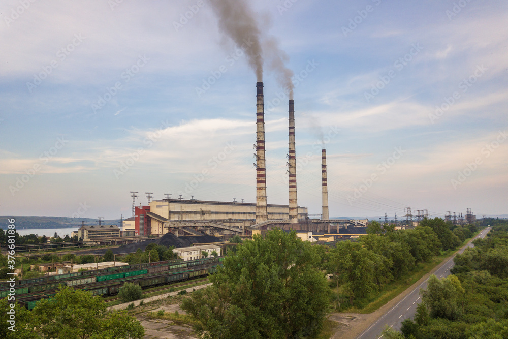 Aerial view of high chimney pipes with grey smoke from coal power plant. Production of electricity with fossil fuel.