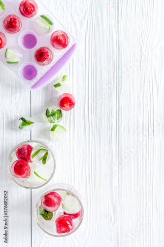 Raspberry and lime in ice cubes on white table top view copy space