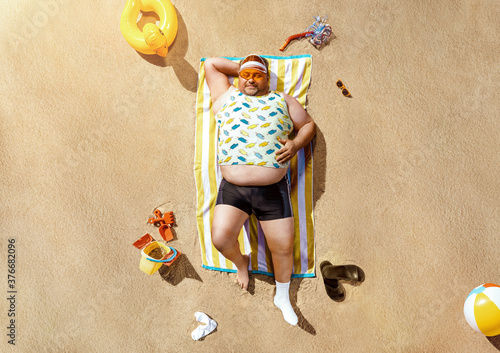 Canvas Print High angle view of funny overweight tourist resting on the beach with copy space