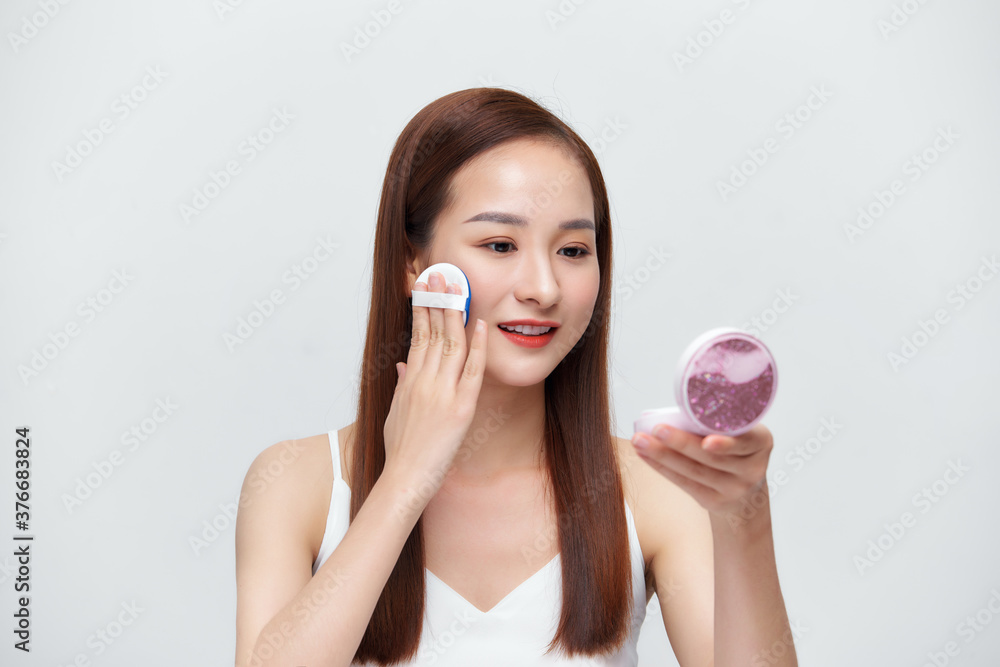 Asian cute young girl holding cosmetic product in white shirt showing her skin Asian cute young girl holding cosmetic product in white shirt showing her skin
