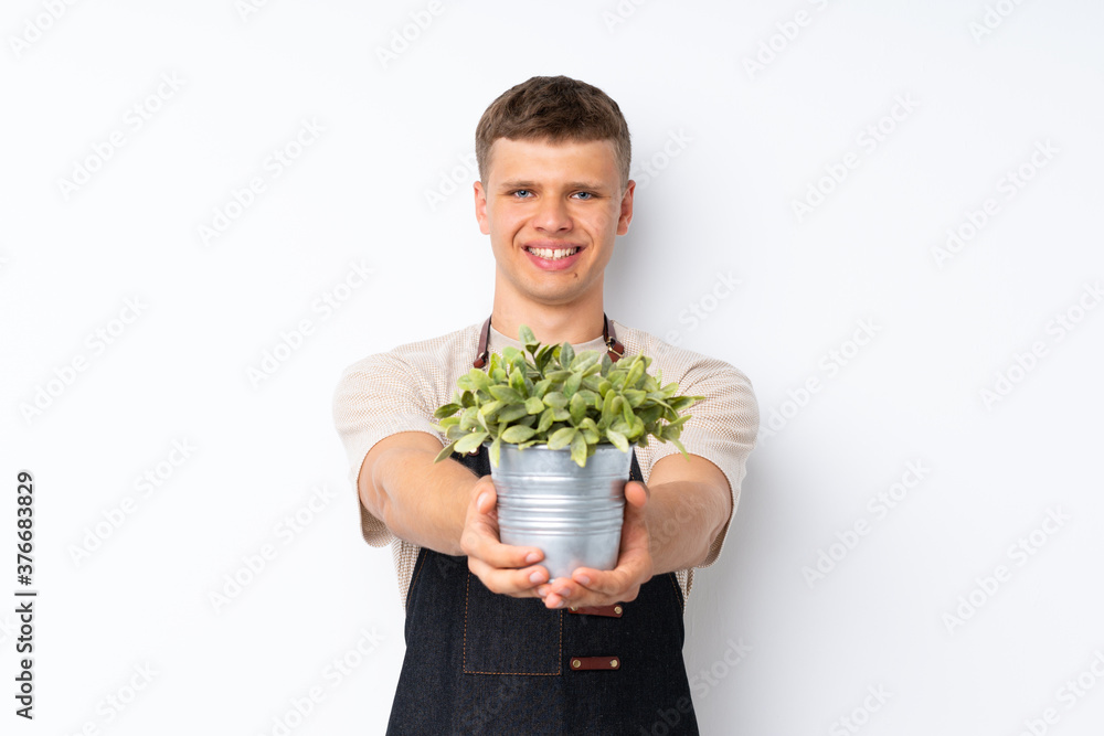 Young handsome man over isolated white background taking a flowerpot Young handsome man over isolated white background taking a flowerpot