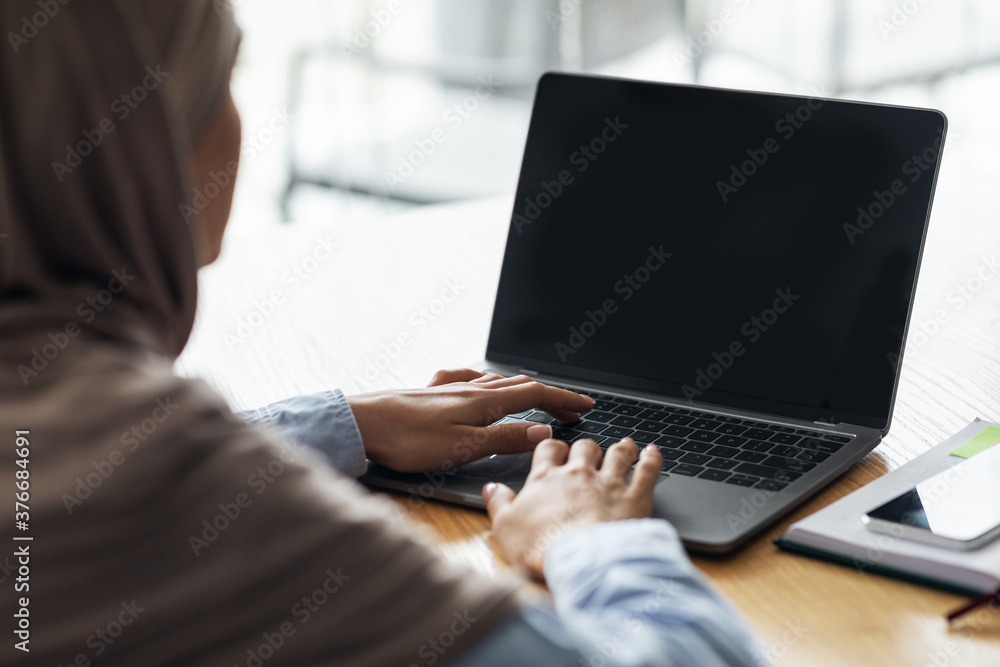 Woman in hijab using laptop with blank screen Woman in hijab using laptop with blank screen