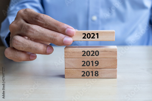 Businessman hand pulling 2021 wooden building blocks on table background. Business planning, Risk Management, Resolution, strategy, solution, goal, New Year New You and happy holiday concepts