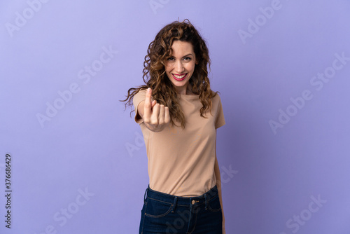 Young caucasian woman isolated on purple background doing coming gesture