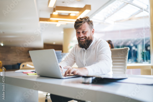 Foto Cheerful businessman typing on laptop in modern workspace