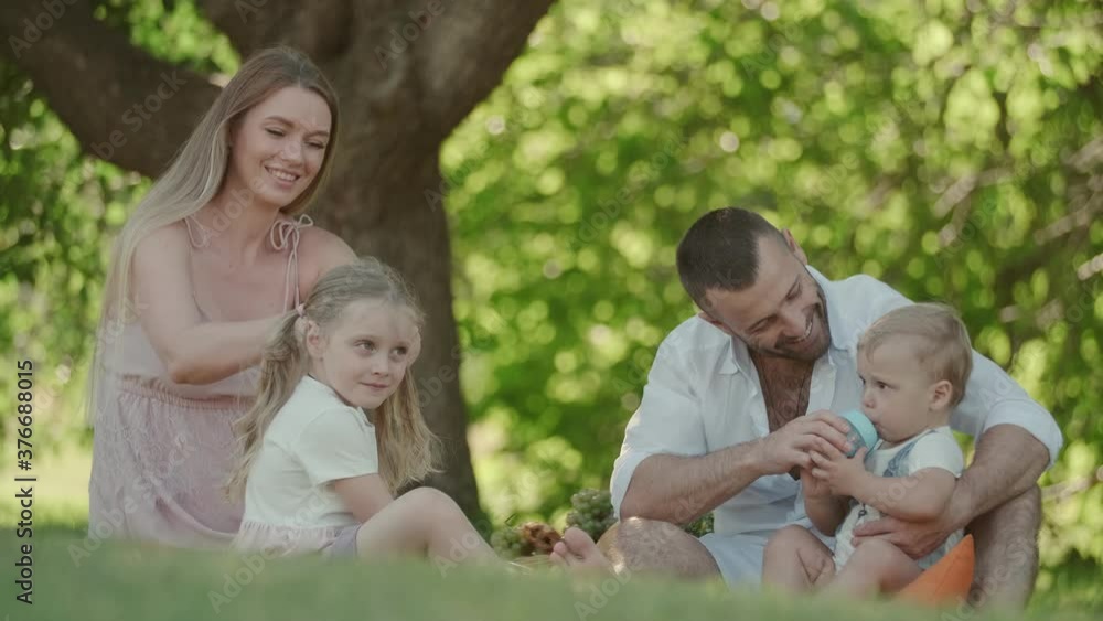 family with children at a picnic. young parents spend time with their son and daughter outdoors