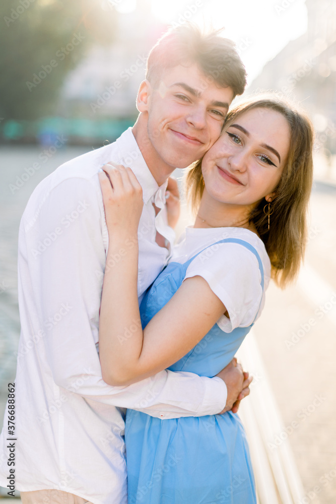 Couple, relationships and love concept. Outdoor city portrait of lovely happy couple, looking at camera with smiles, hugging and enjoying their time together Couple, relationships and love concept. Outdoor city portrait of lovely happy couple, looking at camera with smiles, hugging and enjoying their time together